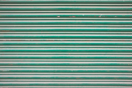 Large green metallic tin stripy fence background with scratches.の写真素材