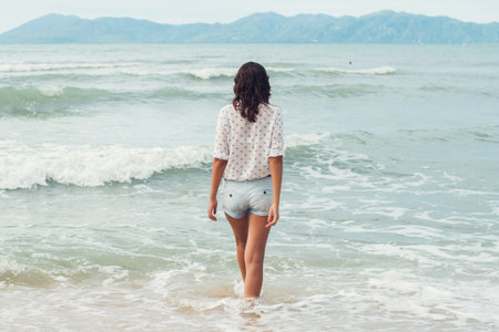 Young woman standing by sea and looking to horizon Summer holidays vacation travel.