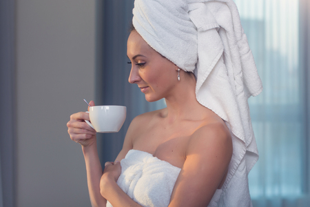 Naked woman with towel on her head and body drinking herbal tea after bathの写真素材