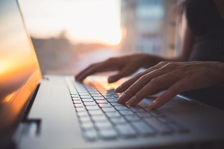 Woman working at home office hand on keyboard close up.