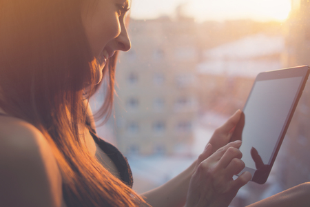 Woman using digital tablet at home sitting near windowの写真素材