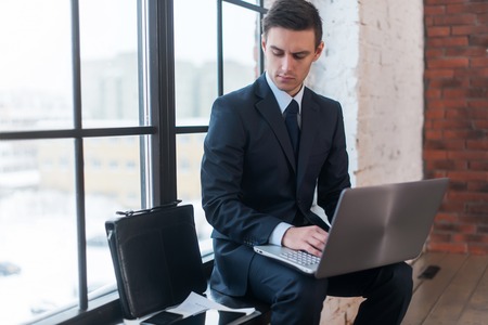 Businessman working on his laptop computer sitting in office.の写真素材