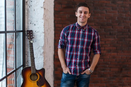 Handsome casual style man with guitar smiling and looking at cameraの写真素材