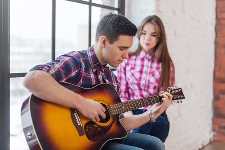 Young man singing playing guitar for his girlfriend.の写真素材