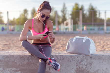 Athlete woman taking picture with smartphone camera, listining music, chatting on the beach summer holidays and vacation healthy lifestyle.の写真素材