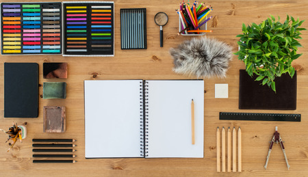 Top view of an artist home studio. Painter worktable in order with a blank sketchpad. Workplace workspace.の写真素材
