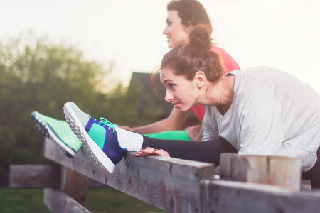 women working stretching leg muscles of back to warm up street staining. Preparation for running...