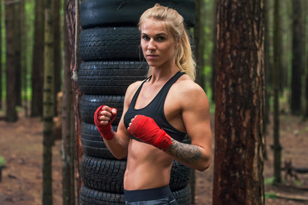 Woman boxer professional fighter posing in boxing stance, working out outdoors.の写真素材