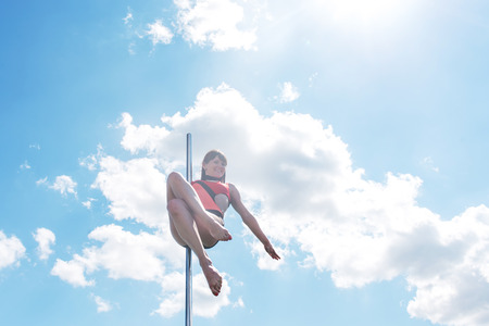 Pole dance fit woman exercising with pylon outdoors.の写真素材