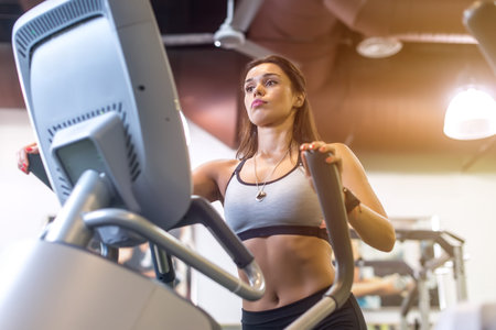 Fit woman doing exercise on a elliptical trainer