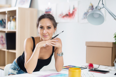 artist woman with long hair paints picture looking at camera.の写真素材