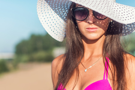 Portrait of beautiful young woman in hat posing in bikini on the beachの写真素材