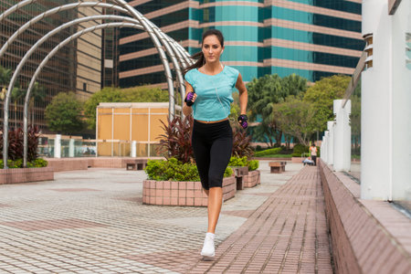 Attractive sporty young woman running on pavement