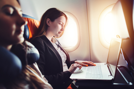 Female entrepreneur working on laptop sitting near window in an airplaneの写真素材
