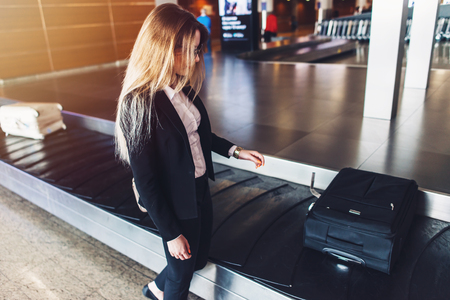 Young businesswoman getting her luggage from baggage claim at airportの写真素材