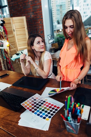 Two colleagues sharing creative ideas discussing new designs in modern studioの写真素材