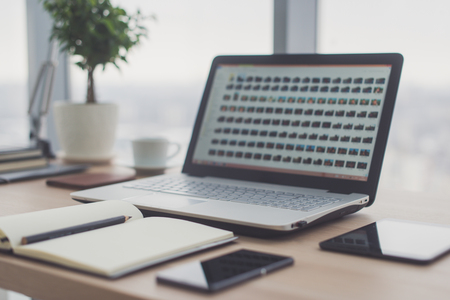 Sideview of office desktop with blank laptop and various tools.の写真素材