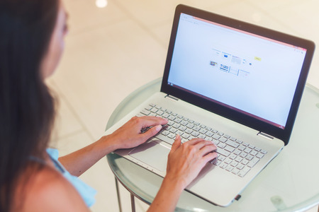 Close-up photo of young business woman working on laptop in white officeの写真素材