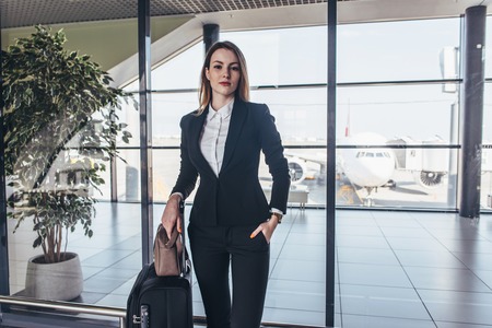 Beautiful airhostess standing in her uniform with her bags ready for a flightの写真素材
