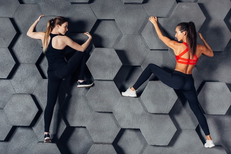 Fit women posing like a climber hanging on decorative wallの写真素材