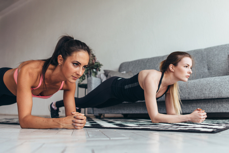Two fit women doing plank exercise on floor at home Training back and press muscles, sport, fitness workoutの写真素材