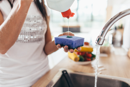 Woman putting cleanser to a sponge. Hand washing dishesの写真素材