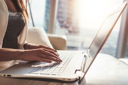 Closeup of female working on laptop sitting in officeの写真素材