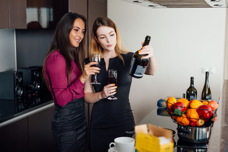Two female friends catching up while drinking wine at homeの写真素材