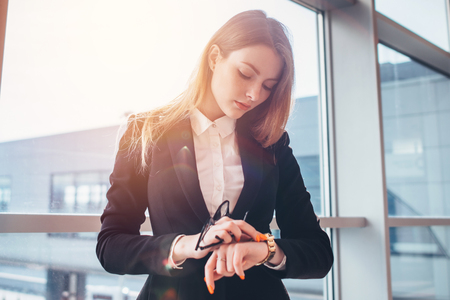 Elegant woman setting her watch standing in airportの写真素材