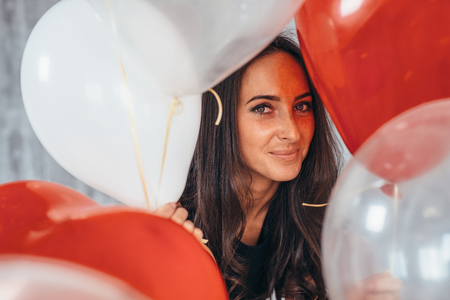 Cheerful young woman with balloons standing and smilingの写真素材