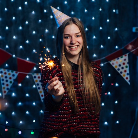 Closeup of young woman holding a sparkling stick at party night.の写真素材