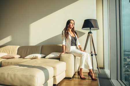 Woman sitting on a sofa at modern apartmentの写真素材
