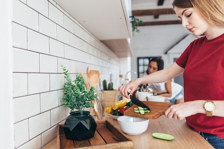 Female hand with knife cutting cucumbers on board.の写真素材