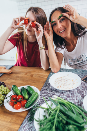 Girls fooling around in the kitchen playing with vegetables.の写真素材