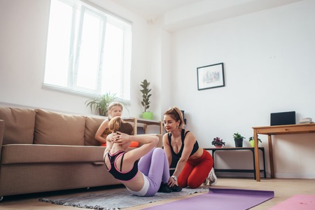 Mother and daughter working out doing crunchesの写真素材
