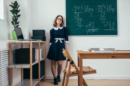 Sad schoolgirl standing in front of blackboard.の写真素材