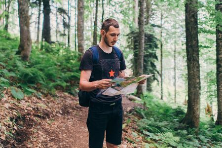 Hiker using a map to locate the destination in forestの写真素材