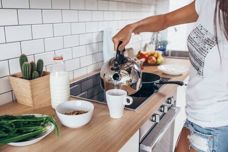 Woman pouring boiling water into a cup from kettle.の写真素材