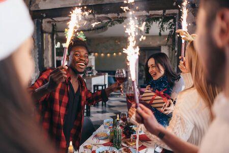 Friends having a party. Smiling people on a holiday toasting drinks burning sparklersの写真素材