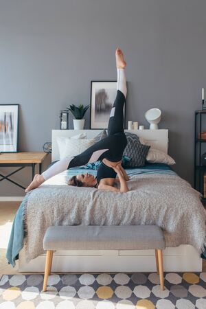 Fit woman does exercise at home on bed.の写真素材