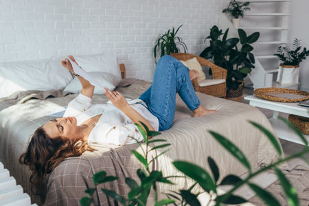 Young woman is lying in her bedroom reading documents