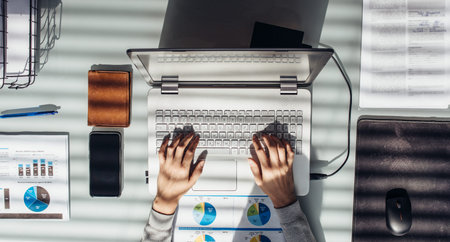 Woman works with laptop at work table.