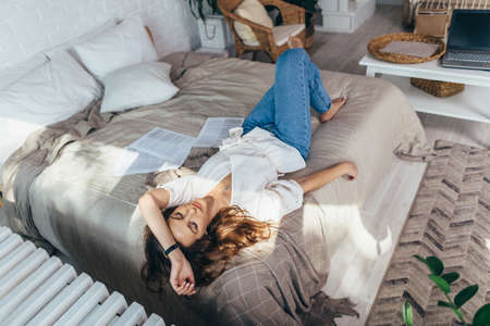 Young woman lying down on sofa with closed eyesの写真素材