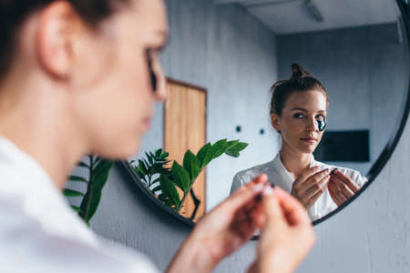 Young woman applies patches under her eyesの写真素材