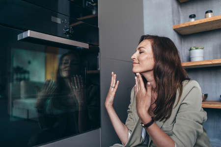 Woman enjoying the aroma of pastries sitting at the ovenの写真素材