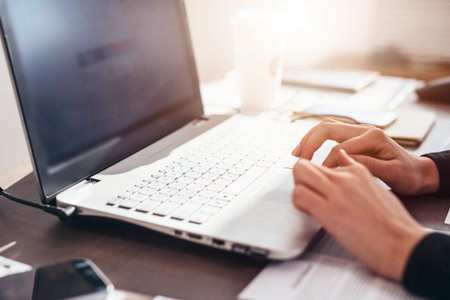 Woman works at home sitting at her desk with her laptop