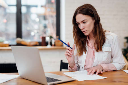 Female doctor has an online appointment sitting at her desk in front of her laptopの写真素材