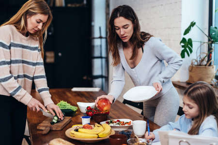 Young women set the table, girl does her homeworkの写真素材