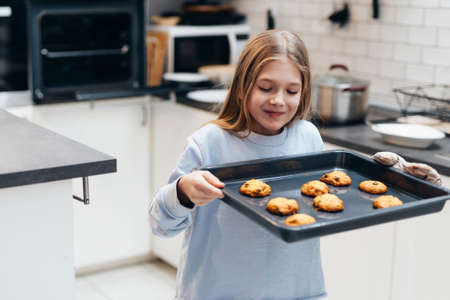 Girl is carrying a tray with cookies that she baked herself.の写真素材