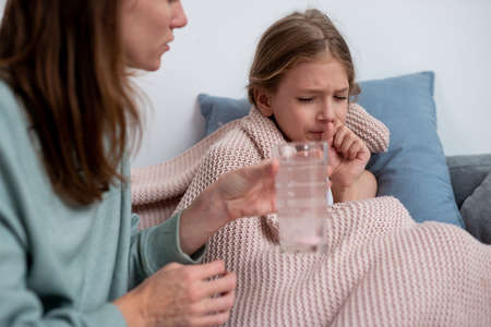 Mother gives her daughter a medicinal drink with a fizzy tabletの写真素材